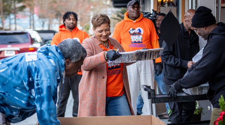 Volunteers load trays of food on Nov. 23, 2023, for delivery around Atlanta. (Steve Schaefer/AJC)