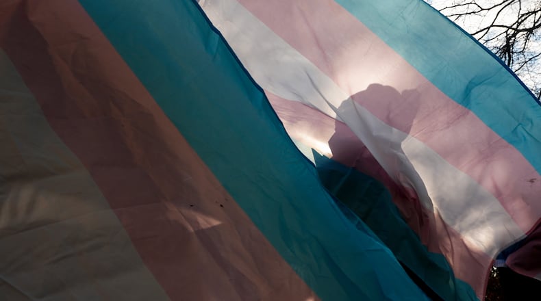 FILE - A protester is silhouetted against a trans pride flag during a pro-transgender rights protest outside of Seattle Children's Hospital, Feb. 9, 2025, in Seattle. (AP Photo/Lindsey Wasson, File)