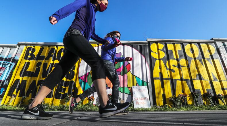 March 22, 2021 Atlanta: Kristen Pollock (foreground) and Brynee Goncher (background) walk past the newly painted Solidarity Mural in 700 block of Wylie Street in Atlanta. There was a weekend of rallies and mural painting to remember those killed in three shootings last Tuesday at spas in metro Atlanta. Eight people, six of them women of Asian ancestry were killed. Xiaojie Tan, 49; and Daoyou Feng, 44; Delaina Ashley Yaun, 33; and Paul Andre Michels, 54, were shot and killed at a spa in Cherokee County. Yong Ae Yue, 63; Soon Chung Park, 74; Suncha Kim, 69; and Hyun Jung Grant, 51 were shot later at two Atlanta spas. (John Spink / John.Spink@ajc.com)