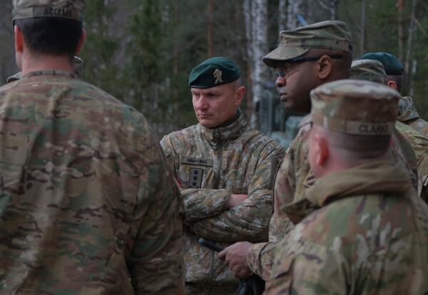 In this image provided by the U.S. Army, U.S. Army soldiers from the 1st Armored Brigade Combat Team, 3rd Infantry Division, along with Lithuanian Army and emergency services personnel, discuss their plan to recover four U.S. soldiers in a U.S. Army M88 Hercules submerged under several meters of water in a swamp near a training area near Pabadre, Lithuania, Thursday, March 27, 2025. (Christopher Saundersn/U.S. Army via AP)