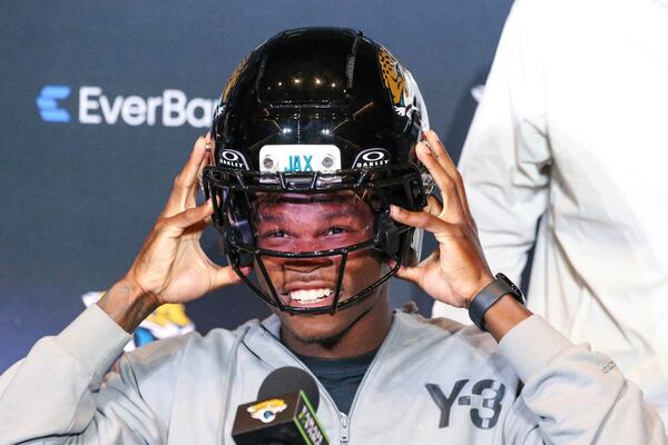 Two-way player Travis Hunter, the Jacksonville Jaguars first round draft pick, second overall, tries on a helmet during an NFL football press conference, Friday, April 25, 2025, in Jacksonville, Fla. (AP Photo/Gary McCullough)
