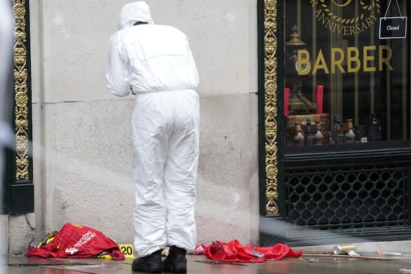 A Forensic officer looks at evidence near the site where a 53-year-old British man plowed a minivan into a crowd of Liverpool soccer fans who were celebrating the city's Premier League championship Monday, injuring more than 45 people in Liverpool, England, Tuesday, May 27, 2025.(AP Photo/Jon Super)