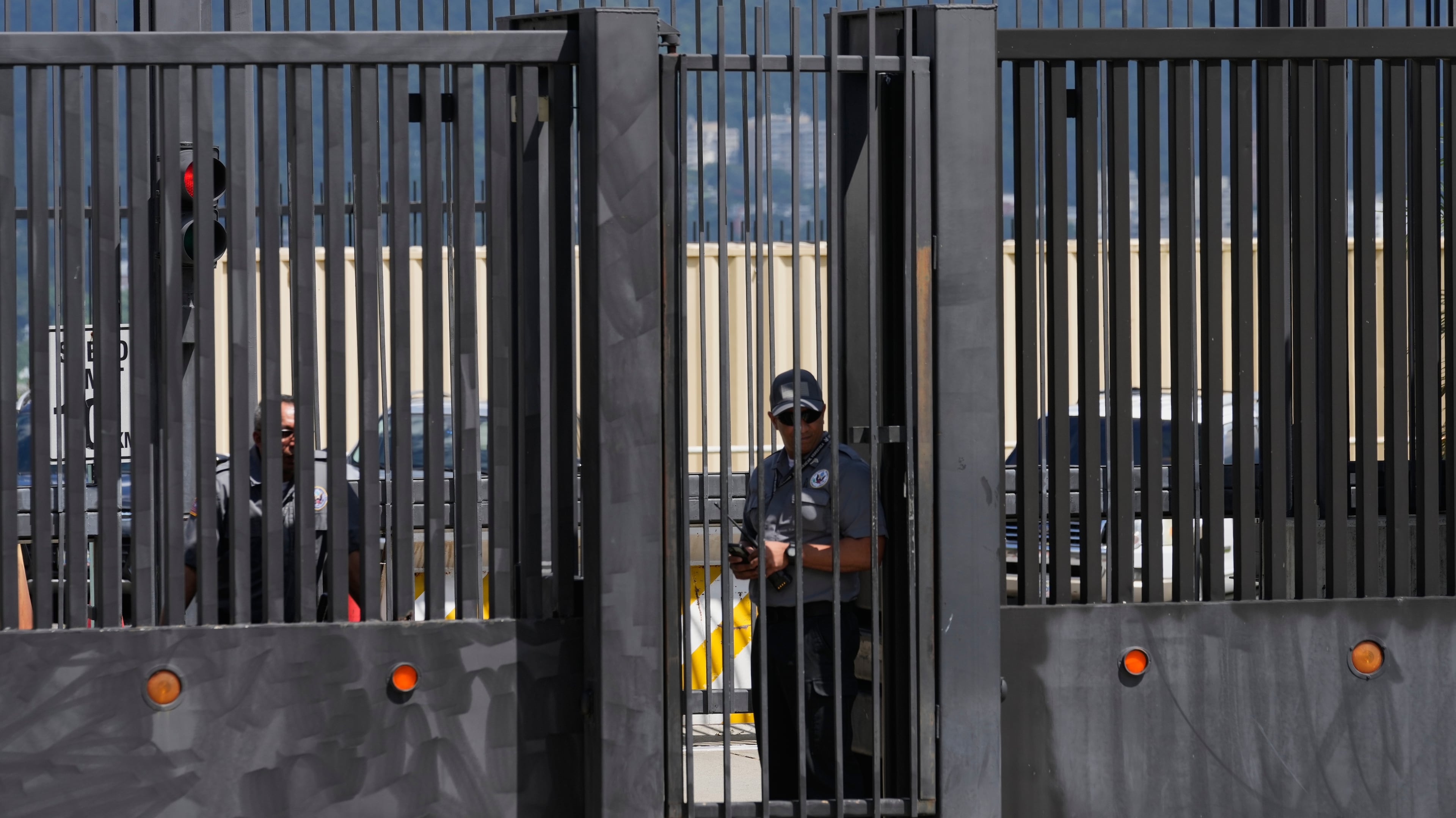 Security officers stand behind the main gate of the United States embassy in Caracas, Venezuela, Monday, Oct. 27, 2025. (AP Photo/Ariana Cubillos)