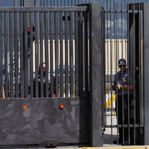 Security officers stand behind the main gate of the United States embassy in Caracas, Venezuela, Monday, Oct. 27, 2025. (AP Photo/Ariana Cubillos)