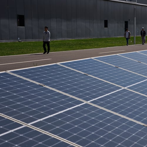 Workers walk by solar panels in the Envision Ordos Modern Energy Equipment Industrial Park in Ordos in northern China's Inner Mongolia province on Friday, June 12, 2026. (AP Photo/Ng Han Guan)
