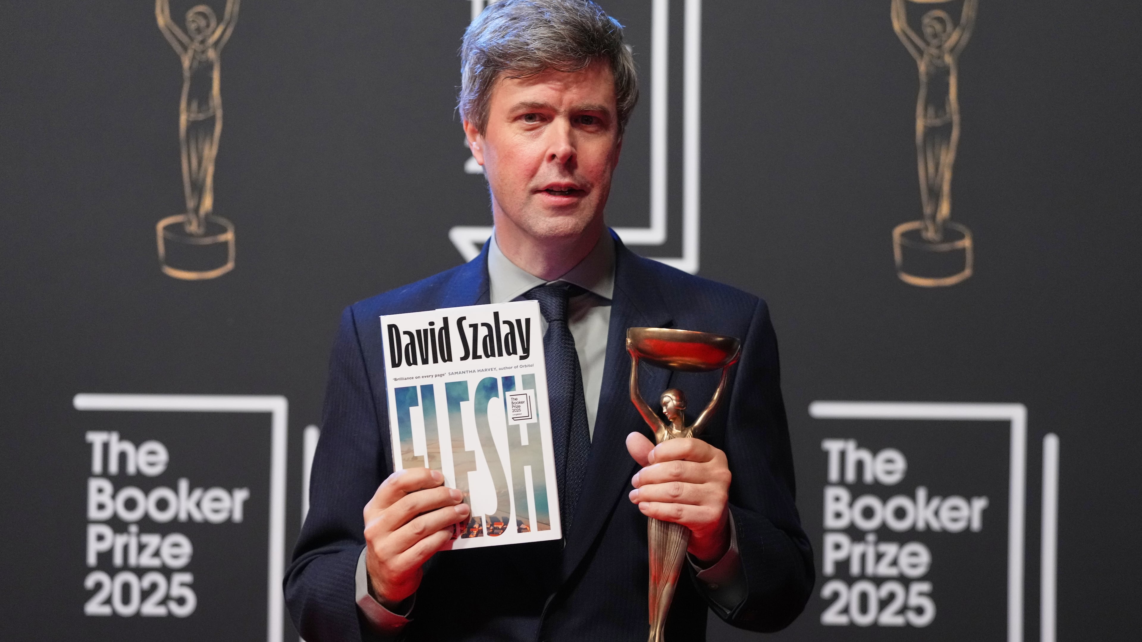 Hungarian-British author David Szalay poses for photographers with the trophy after winning the Booker Prize 2025 for his book 'Flesh' during a ceremony at Old Billingsgate in London, Monday, Nov. 10, 2025. (AP Photo/Kirsty Wigglesworth)