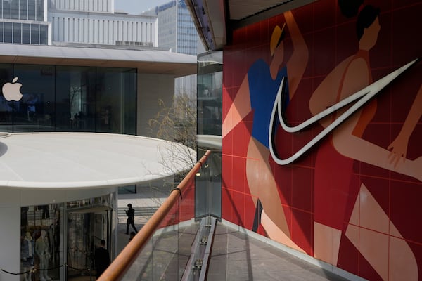 A man walks past Apple and Nike stores in Beijing, China, Friday, April 4, 2025. (AP Photo/Ng Han Guan)