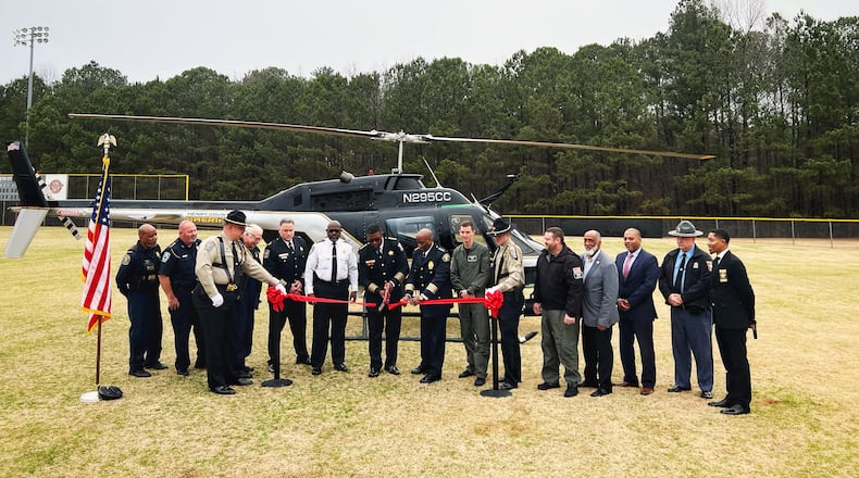 Henry County Sheriff Reginald Scandrett (center) cuts a ribbon in front of his agency's new helicopter while flanked by other leaders from local government and neighboring law enforcement agencies.