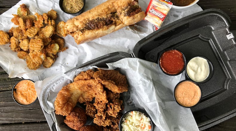A feast from the Po’Boy Shop in Decatur. Clockwise from left: Fried pickles, boudin balls, gumbo, a combo platter with fried oysters, grouper, hush puppies, and slaw; and a Surf & Turf po’boy (fried shrimp with roast beef and its debris).
Wendell Brock for The Atlanta Journal Constitution