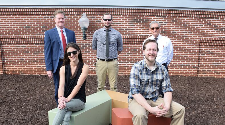 With the second of two sculptures, standing, L-R, are Geo Sipp, director of the KSU School of Art and Design; Page Birch, studio technician/coordinator, KSU School of Art and Design and Kennesaw Economic Development Director Robert Fox. Seated are KSU artists Megan Pace and Thomas Daniel. Courtesy of Kennesaw