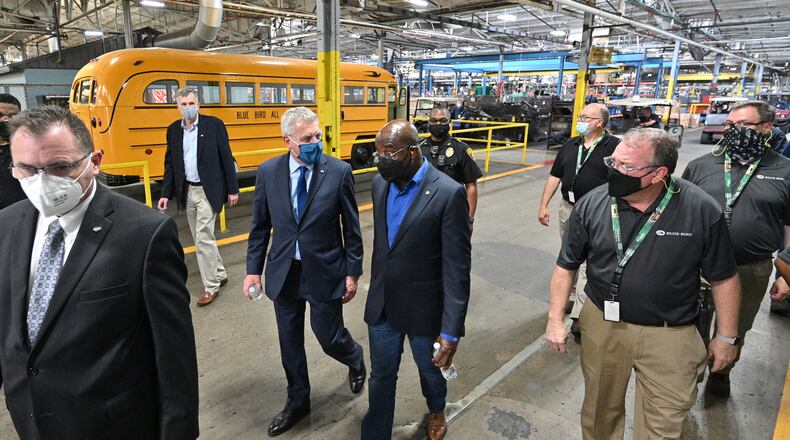 Blue Bird officials talk with Sen. Rev. Raphael Warnock (center right), during a tour of manufacturing facility at Blue Bird in 2021. The U.S. Department of Energy announced Thursday that it is giving Blue Bird $80 million to convert an old factory to making electric buses. (Hyosub Shin / Hyosub.Shin@ajc.com)