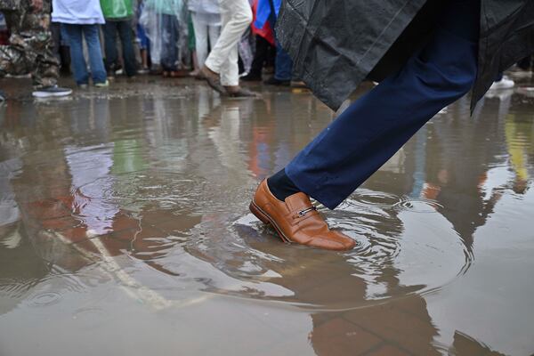 A race fan walks through a puddle at Churchill Downs before the 151st running of the Kentucky Derby horse race Saturday, May 3, 2025, in Louisville, Ky. (AP Photo/Jon Cherry)