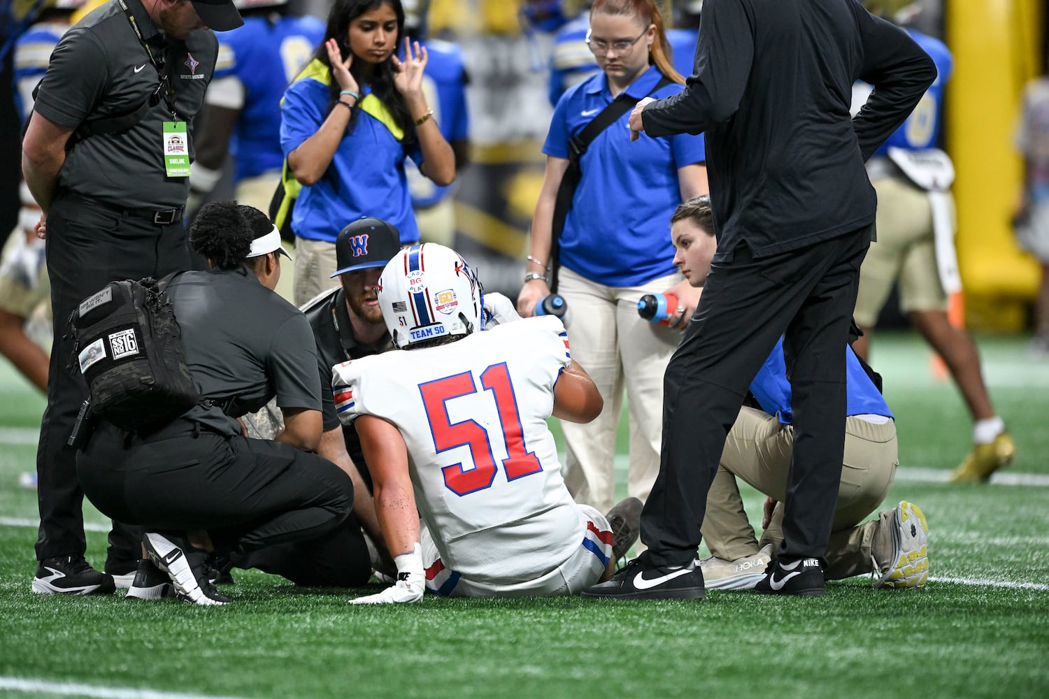 Trainers check on Walton center Rocco Tenebruso (51) after a play during the first half of the Corky Kell Classic football game Saturday, August 16, 2025 at the Mercedes-Benz Stadium. (Daniel Varnado/For the Atlanta Journal-Constitution)