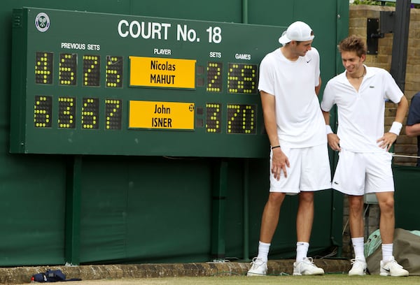 FILE - John Isner of the US and France's Nicolas Mahut, right, pose for a photo next to the scoreboard following their epic men's singles match at the All England Lawn Tennis Championships at Wimbledon, Thursday, June 24, 2010. (AP Photo/Alastair Grant,Pool,File)