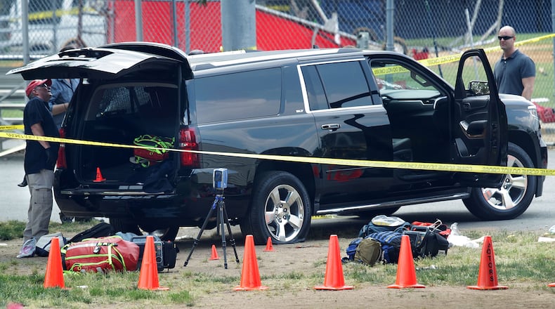 Investigators survey a black SUV with a flat tire and a hole on its windshield outside the Eugene Simpson Stadium Park, where U.S. House Majority Whip Rep. Steve Scalise, R-La., and multiple congressional aides were shot by a gunman during a Republican baseball practice. Alex Wong/Getty Images