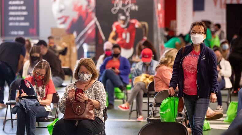 Fulton County school employees sit in the holding area after receiving their vaccination shot at the Mercedes-Benz Stadium. STEVE SCHAEFER FOR THE ATLANTA JOURNAL-CONSTITUTION