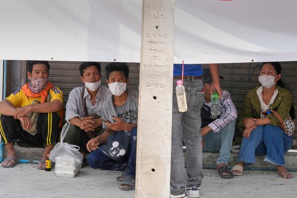 Relatives wait under a shade near the damaged construction site of a high-rise building in Bangkok, Thailand, Saturday, March 29, 2025, as rescuers search for victims following its collapse after Friday's earthquake. (AP Photo/Manish Swarup)