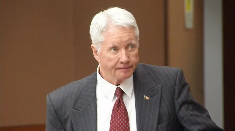 Tex McIver, on trial for the murder of his wife, Diane McIver, looks away from the screen as the jury is show video of her being unloaded and taken into the emergency room of Emory University Hospital on the night she was shot.