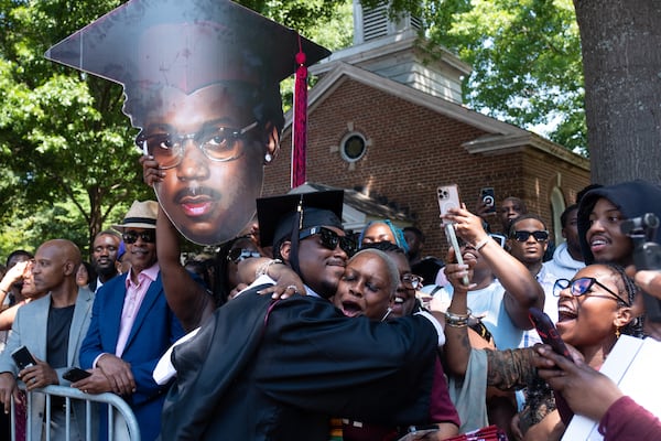 Geondre Baldwin hugs Auntie Tasha Allen-Maximo under a huge cutout of himself held by his mother Nefertari Soleberry after receiving his diploma at the Morehouse College graduation Sunday, May 17, 2026. (Ben Gray for the AJC)