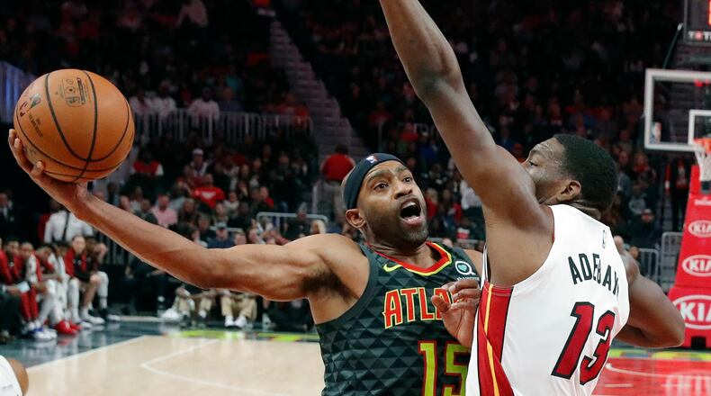 Hawks forward Vince Carter (15) goes up for a shot as Miami Heat center Bam Adebayo (13) defends. (AP Photo/John Bazemore)