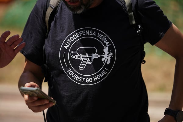 A person wears a t shirt with the message reading 'Neighborhood auto defense - Tourists go home' during a protest against overtourism in Barcelona, Spain, Sunday, June 15, 2025. (AP Photo/Pau Venteo)