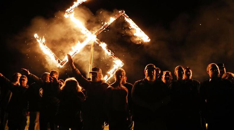 Members of the National Socialist Movement, a neo-Nazi group, hold a swastika-burning in Draketown, Ga., on April 21, 2018, following their rally that day in Newnan, Ga. An Ohio haunted house apologizes for hosting a Halloween ‘Swastika Saturday’ party.