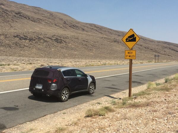 A preproduction Kia Sportage, seen in camouflage as it was still in its testing phase, is seen driving on a grade during hot weather testing in the California desert. (Courtesy Matt Degen/Cox Automotive)