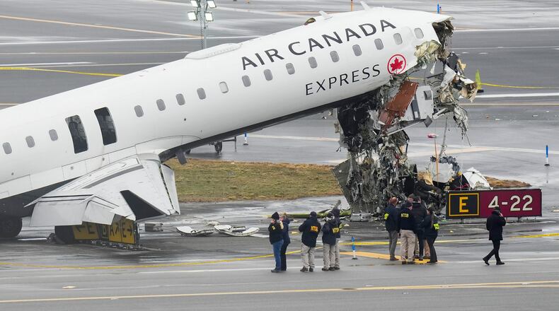 FILE - Officials with the National Transportation Safety Board investigate the site, March 23, 2026, where an Air Canada jet came to rest after colliding with a Port Authority firetruck at LaGuardia Airport, shortly after landing Sunday night in New York. (AP Photo/Seth Wenig, File)