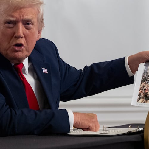 President Donald Trump holds up a photograph as he speaks to reporters after speaking to troops via video from his Mar-a-Lago estate on Thanksgiving, Thursday, Nov. 27, 2025, in Palm Beach, Fla. (AP Photo/Alex Brandon)