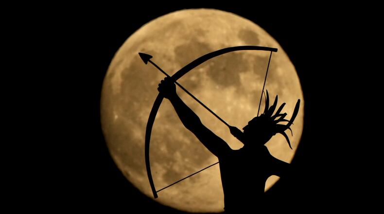FILE - The bronze sculpture titled "Ad Astra," depicting a Kansa warrior, perched atop the Kansas State Capitol dome, is silhouetted against the nearly full moon, Nov. 14, 2024, on the eve of the final supermoon of the year in Topeka, Kan. (AP Photo/Charlie Riedel, File)