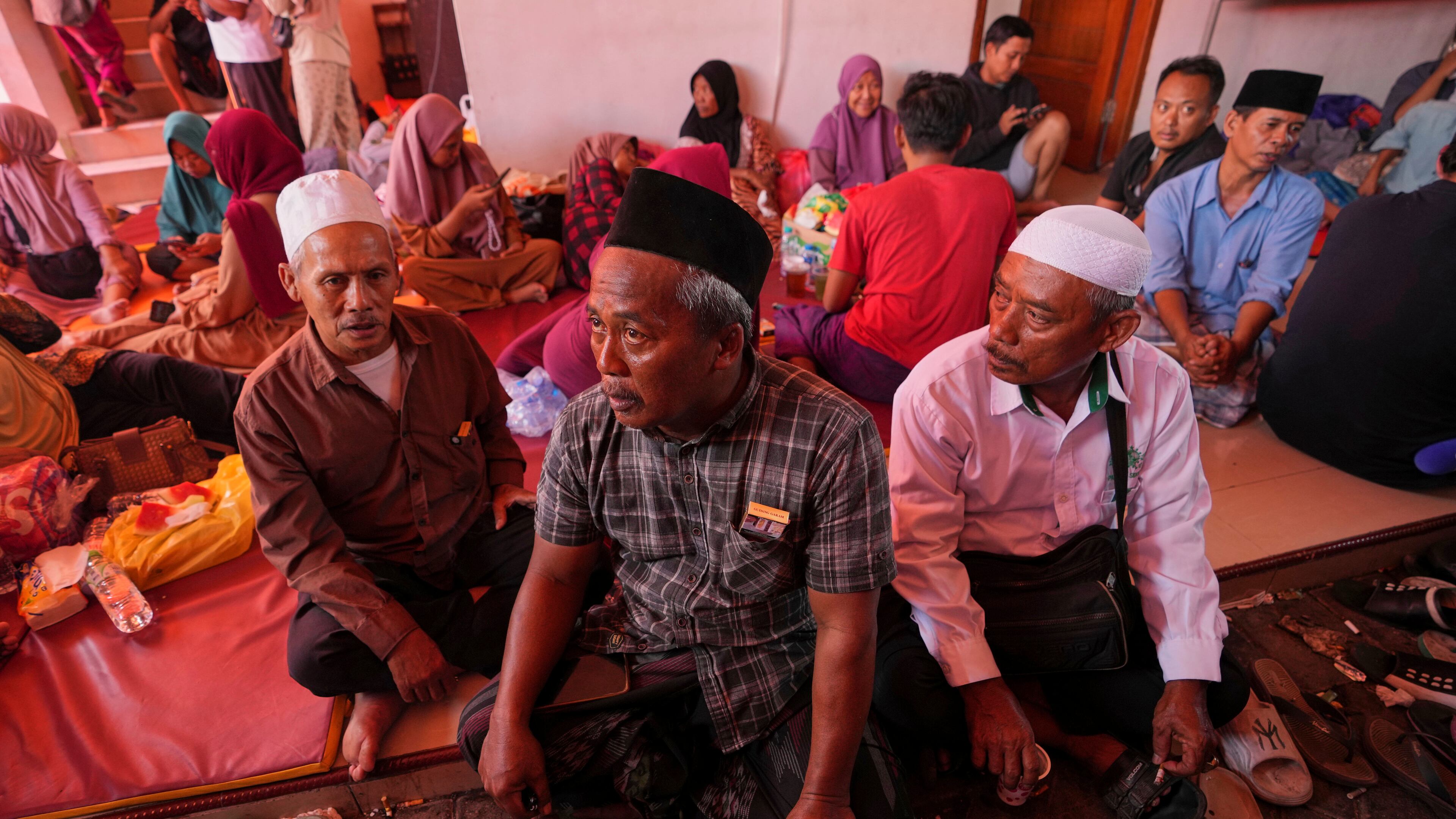 Mohammad Solehoddin, center, whose son has not been accounted for after a building under construction collapsed Monday at an Islamic boarding school, waits with other family members as rescue efforts are underway, in Sidoarjo, East Java, Indonesia, Thursday, Oct. 2, 2025. (AP Photo/Achmad Ibrahim)