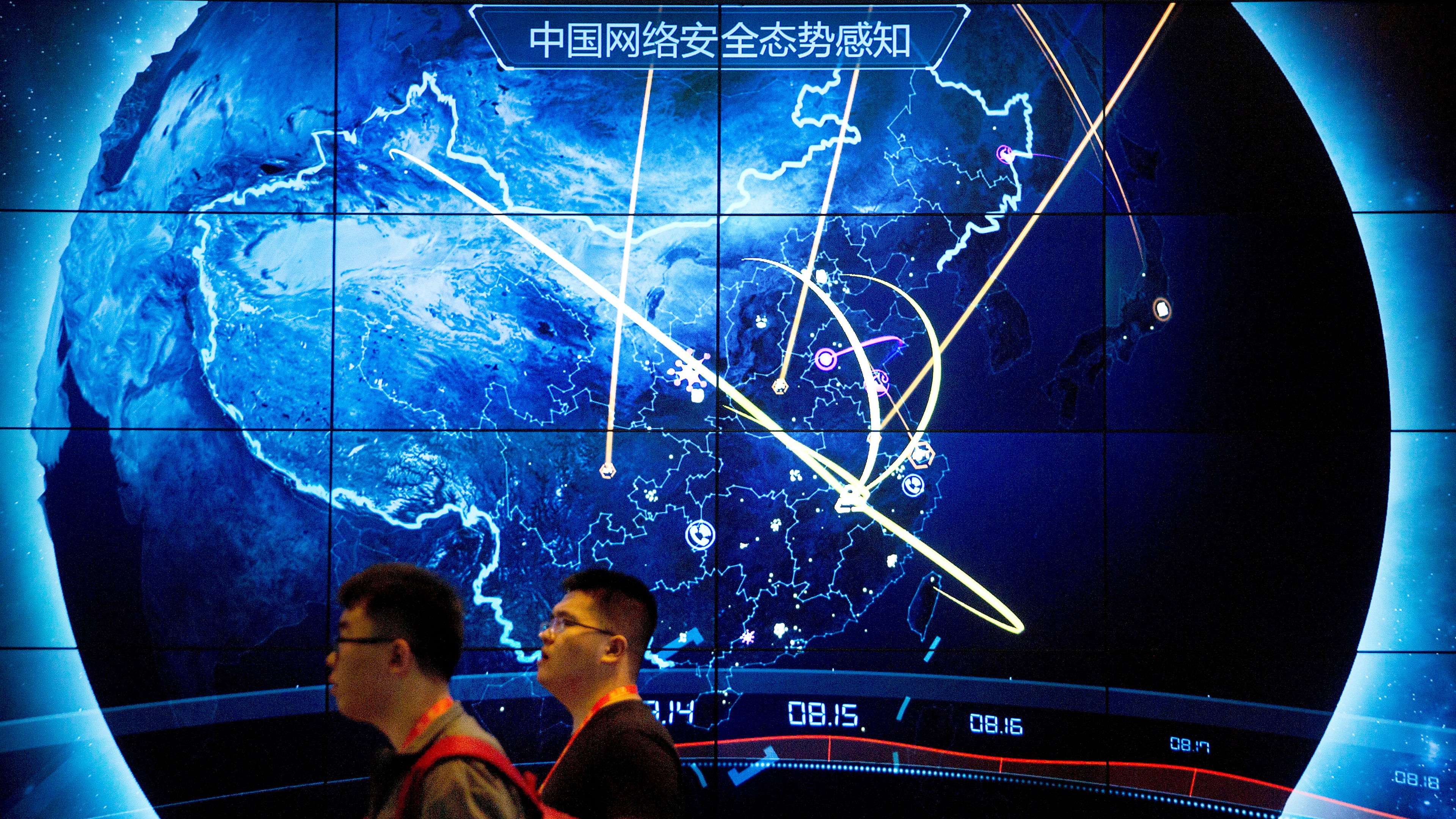 FILE - Attendees walk past an electronic display showing recent cyberattacks in China at the China Internet Security Conference in Beijing on Sept. 12, 2017. (AP Photo/Mark Schiefelbein, File)