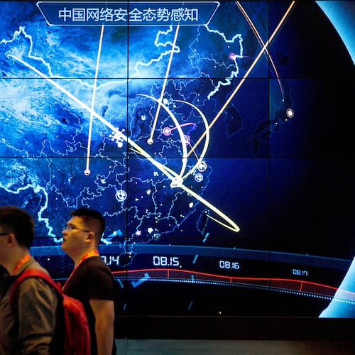 FILE - Attendees walk past an electronic display showing recent cyberattacks in China at the China Internet Security Conference in Beijing on Sept. 12, 2017. (AP Photo/Mark Schiefelbein, File)