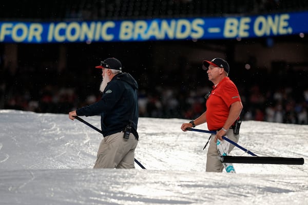 Grounds crew work during a rain delay in the ninth inning of a baseball game between the Atlanta Braves and the Los Angeles Dodgers, Friday, May 2, 2025, in Atlanta. (AP Photo/Mike Stewart)