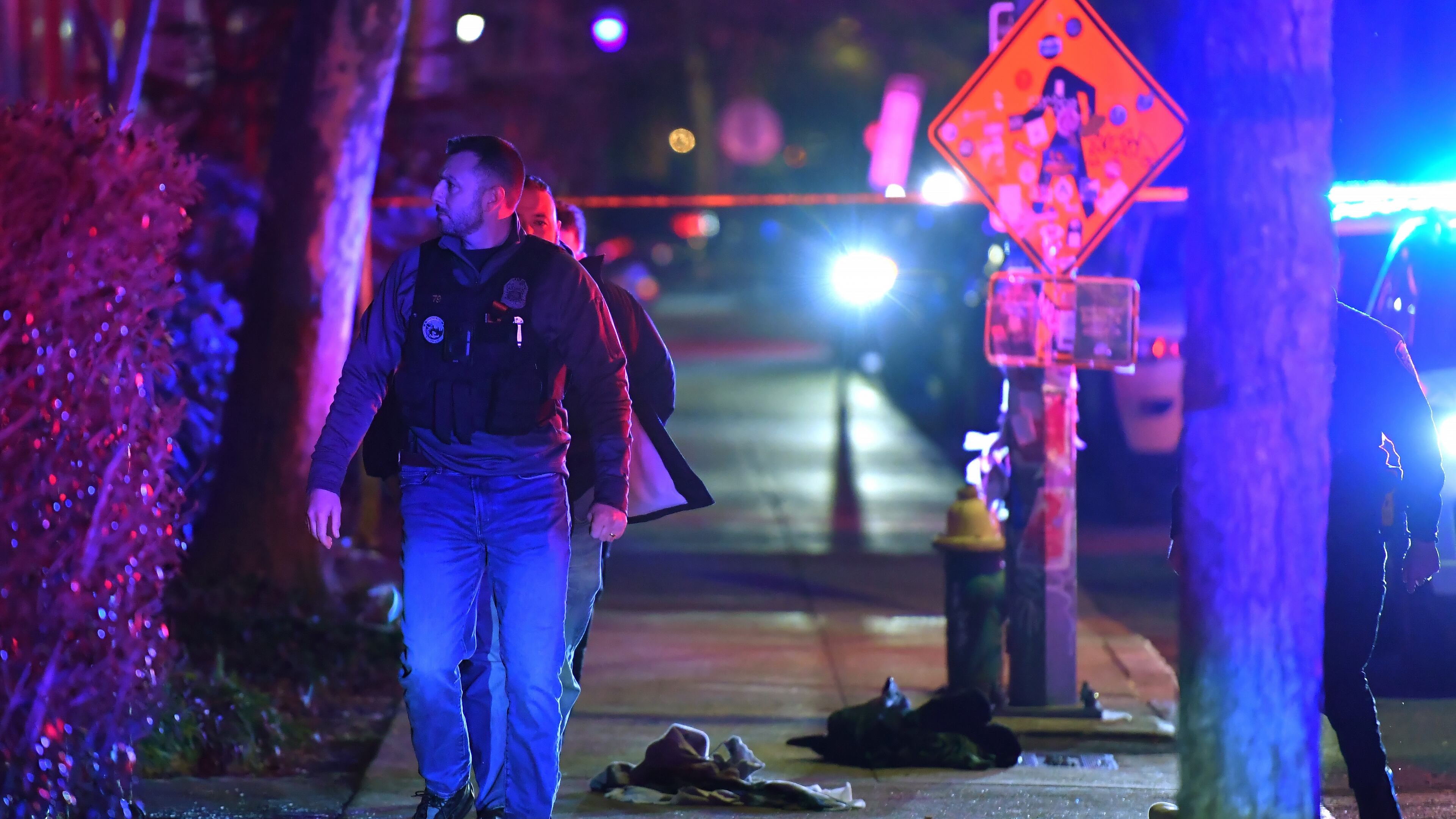 A law enforcement official walks past articles of clothing on a sidewalk near an entrance to Brown University, Saturday, Dec. 13, 2025, in Providence, R.I., during the investigation of a shooting. (AP Photo/Steven Senne)