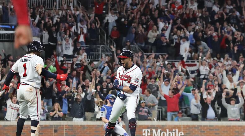 Braves outfielder Eddie Rosario (right) looks at upcoming batter Ozzie Albies and reacts to his three-run homer that proved to be the game winner while Braves fans erupt for the 4-1 lead over the Dodgers during the fourth inning in Game 6 of the NLCS on Saturday, Oct. 23, 2021, in Atlanta. Curtis Compton / Curtis.Compton@ajc.com