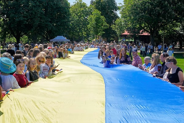 People from Ukraine hold a giant Ukrainian flag during a family meeting with their Eurovision band Ziferblat in a park in Basel as part of the 69th Eurovision Song Contest week, in Basel, Switzerland, Thursday, May 15, 2025. (AP Photo/Martin Meissner)