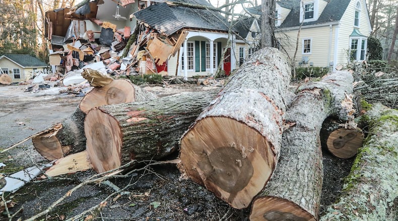 A 47-year-old man became pinned between his bed and a large tree when the tree crashed into his second-floor bedroom and he fell to the garage below, officials said.