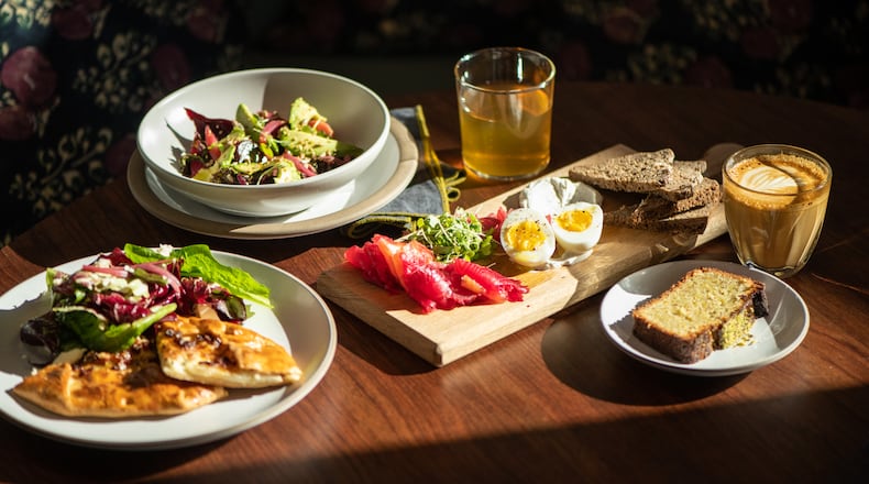Le Bon Nosh's pear galette (left), beet salad (upper left), beet-cured salmon (center) and pistachio cake (lower right) are shown with tea and latte. (Mia Yakel for The Atlanta Journal-Constitution)