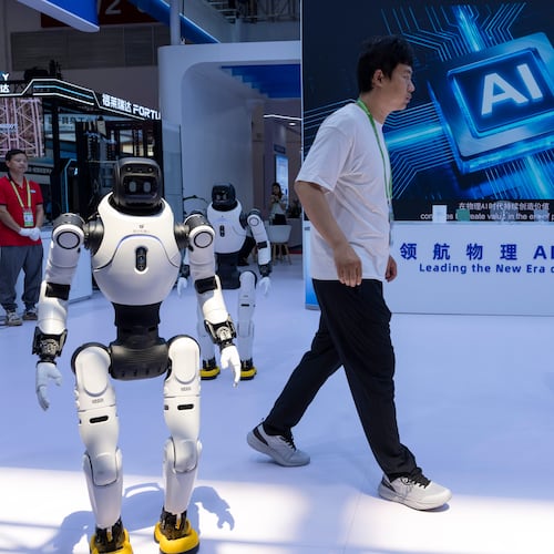 FILE- A worker passes by robots from Chinese company Lens at the China International Supply Chain Expo in Beijing on Monday, June 22, 2026. (AP Photo/Ng Han Guan, File)