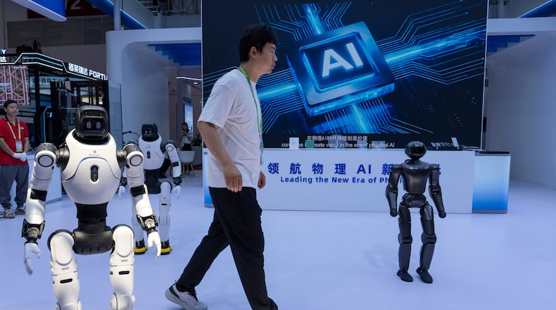 FILE- A worker passes by robots from Chinese company Lens at the China International Supply Chain Expo in Beijing on Monday, June 22, 2026. (AP Photo/Ng Han Guan, File)