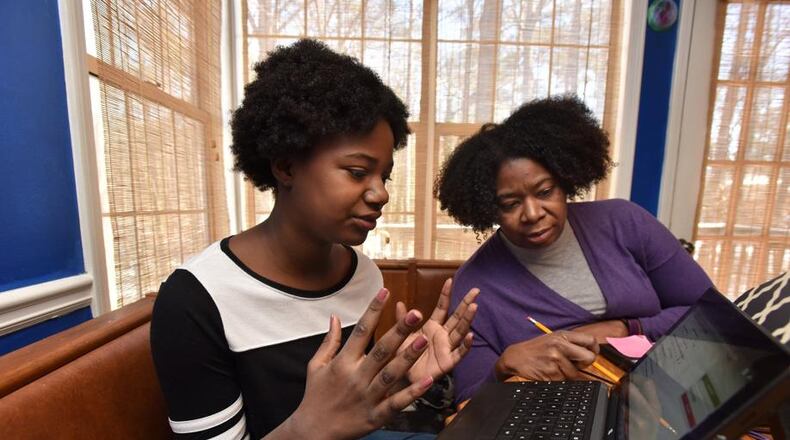 Paula Richards-Bell, eighth-grade teacher at Jordan Middle School, helps her daughter Olivia Bell, 11, who is a sixth-grader at Jordan Middle School, with her digital learning day assignment at their home in Lawrenceville on Thursday, Jan. 18, 2018. Gwinnett County schools, the largest school district in the state, launched its digital learning program on Jan. 8, when the threat of ice and frigid temperatures led administrators to close schools. HYOSUB SHIN / HSHIN@AJC.COM