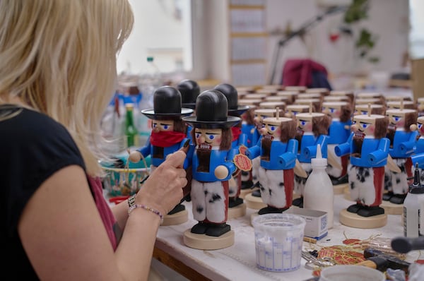 A woman works on nutcrackers of a cowboy at the Steinbach-Volkskunst nutcracker factory in Marienberg, Germany, Tuesday, April 15, 2025. (AP Photo/Markus Schreiber)