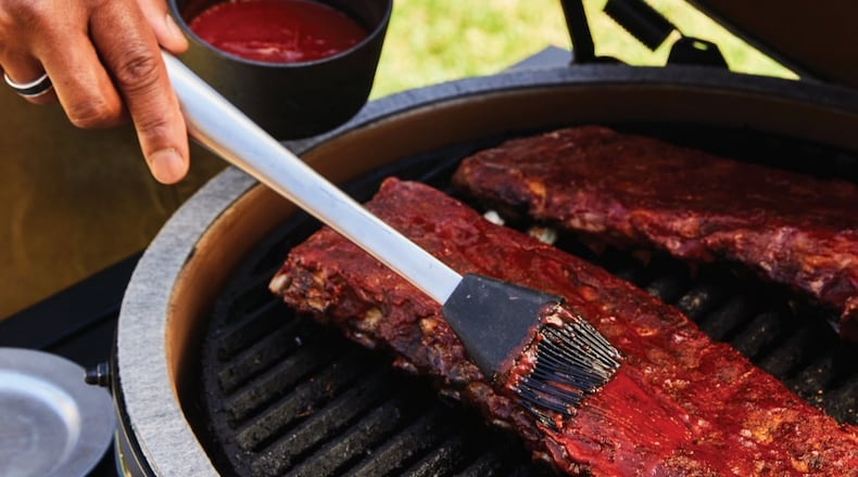 Grill master David Rose adds sauce to his BBQ ribs.
