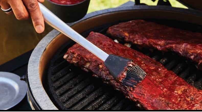 Grill master David Rose adds sauce to his BBQ ribs.