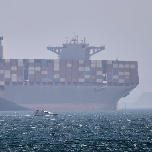 A container ship sits at anchor as a small motorboat passes in the foreground in the Strait of Hormuz off Bandar Abbas, Iran, Saturday, May 2, 2026. (Amirhosein Khorgooi/ISNA via AP)