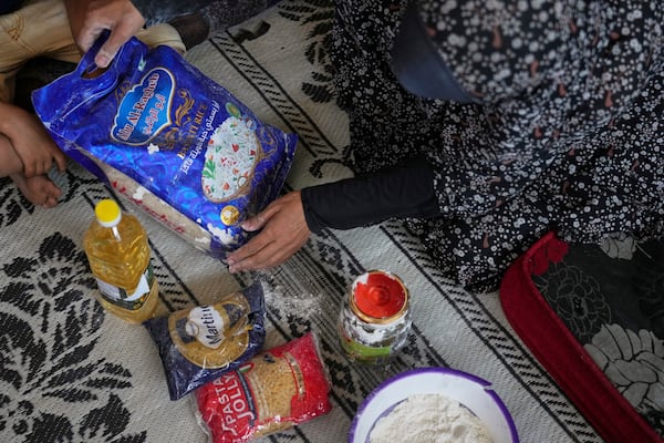 Anwaar Saleh, 32, displays the donated food her husband, Omar al-Hobi, collected at a distribution center run by private contractor the Gaza Humanitarian Foundation in the southern Gaza Strip, after he arrived at their family's tent in Khan Younis, Tuesday, June 10, 2025. (AP Photo/Abdel Kareem Hana)