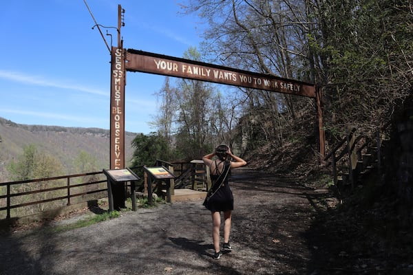 West Virginia Coal Festival teen beauty pageant winner Ava Johnson, 16, walks under a sign urging miners to work safely at the former Kay Moor coal town and camp in the New River Gorge National Park and Preserve near Fayetteville, W.Va., Thursday, April 17, 2025, (AP Photo/Leah Willingham)