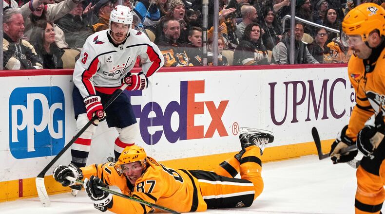 Pittsburgh Penguins' Sidney Crosby (87) gets of a pass to Bryan Rust, right, with Washington Capitals' Matt Roy (3) defending during the second period of an NHL hockey game in Pittsburgh, Thursday, Nov. 6, 2025. (AP Photo/Gene J. Puskar)