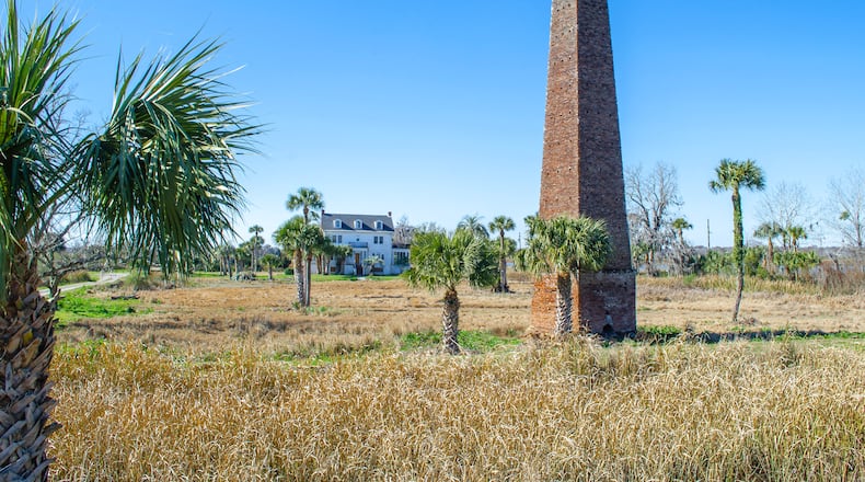 One mile south of Darien on U.S. Highway 17 sits Butler Island, the former site of a large rice plantation. A tall brick chimney, the remains of a steam-powered rice mill, is one of two surviving structures from the original plantation. Over a two-day period in 1859, 436 people enslaved at Butler Island Plantation were sold at auction in Savannah, an event referred to as the Weeping Time. The white house on the current property was built in the mid-1920s by former owner Col. T.L. Huston. Today the Georgia Department of Natural Resources manages the grounds. The Huston House, which is not inhabited nor maintained, was placed on the Georgia Trust for Historic Preservation’s “Places in Peril” list in 2019. COURTESY OF THE COLLECTIVE & CO